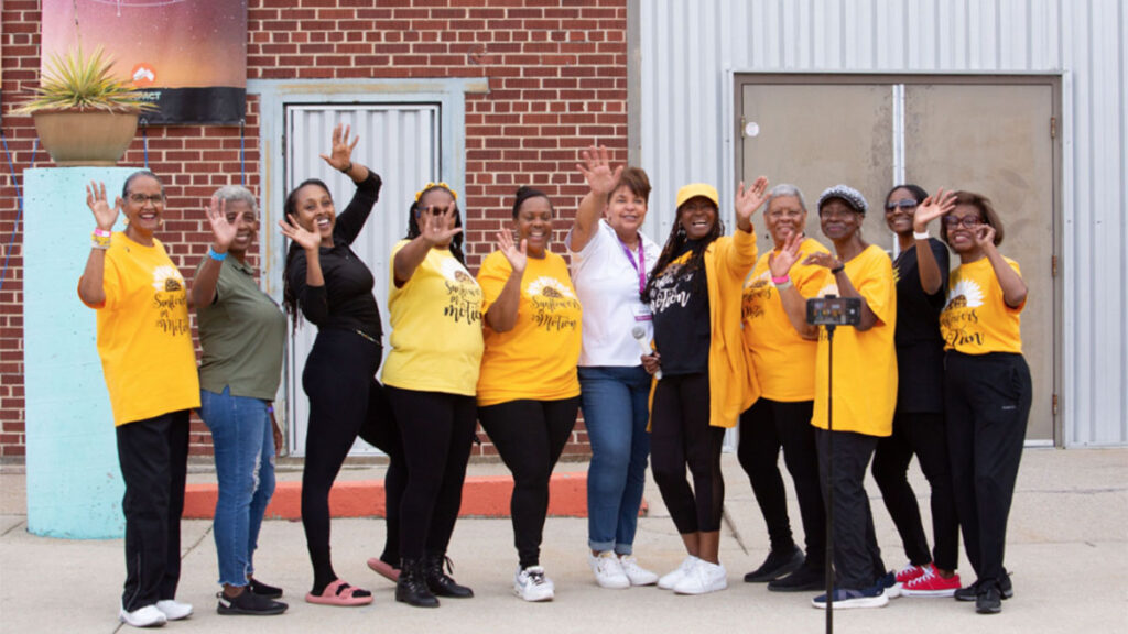 Group of volunteers and attendees of a festival stand together outside the venue in a joyful group pose