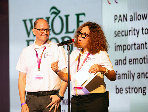 PAN leaders Kevin and Kim on stage, Kim talking in a microphone