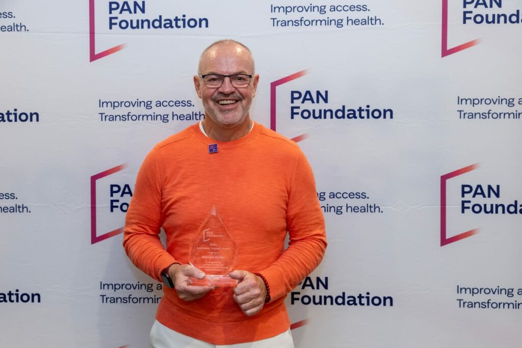 Portrait of Michael Riotto holding a patient advocate award at a PAN event